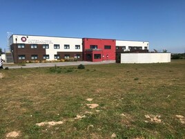Un moderno edificio Inter-Hotel con techo plano, zona de estacionamiento y un campo de césped delantero.