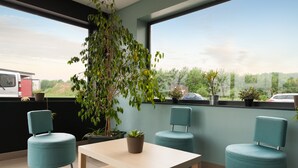 Een modern balkon met uitzicht op een voertuig en groen, met een tafel en twee stoelen.