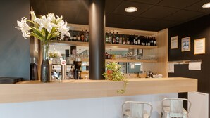 Een bar met een toonbank, flessenkasten en twee barkrukken.