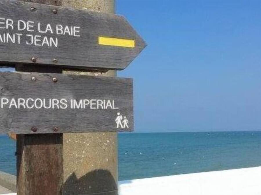 A wooden signpost with directional arrows and text indicating 'Sentier de la Baie Saint Jean' and 'Parcours Imperial'.