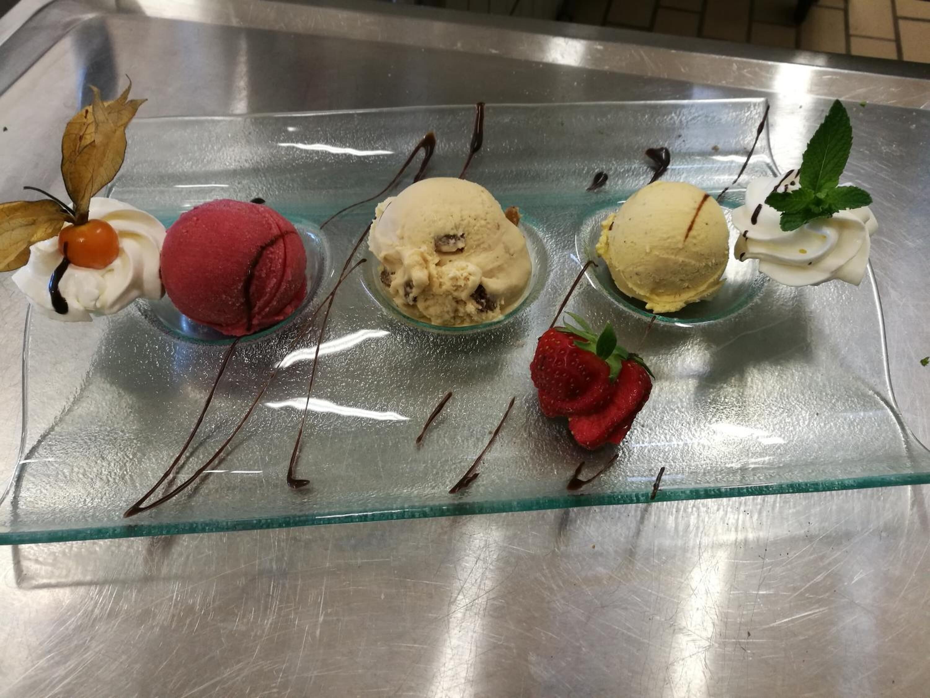 A dessert tray with four scoops of ice cream and a strawberry.