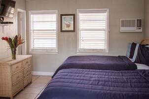 A bedroom with two beds, a dresser, a TV, and a picture on the wall.