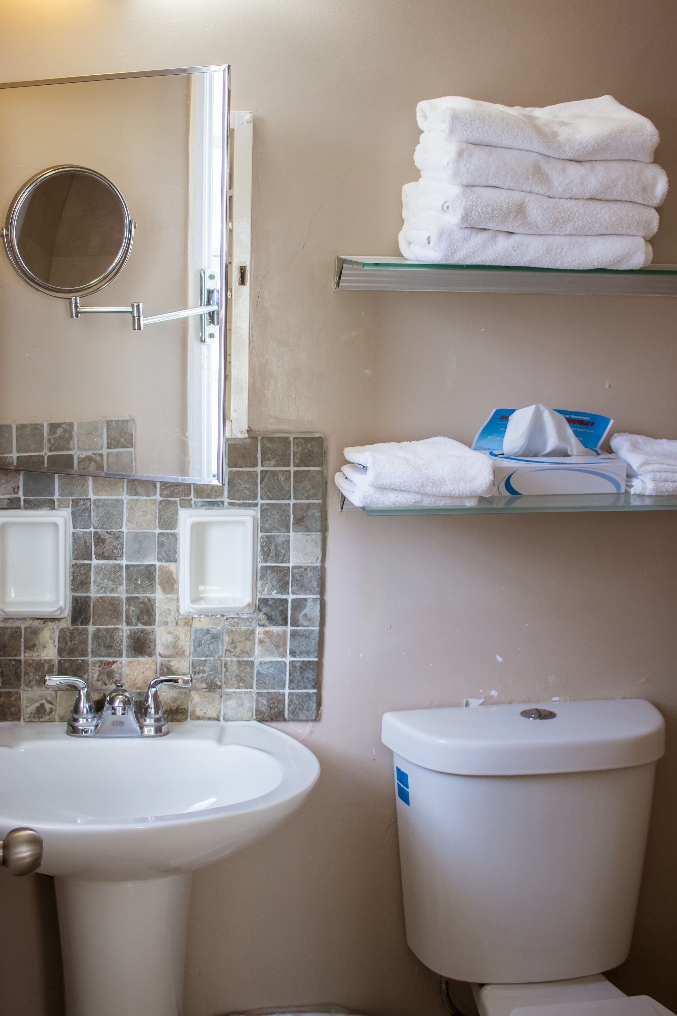 A bathroom with a sink, mirror, and stacked towels.