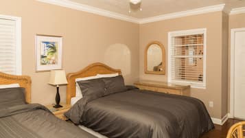 A bedroom with two beds, a ceiling fan, a framed picture, a mirror, and a window with blinds.