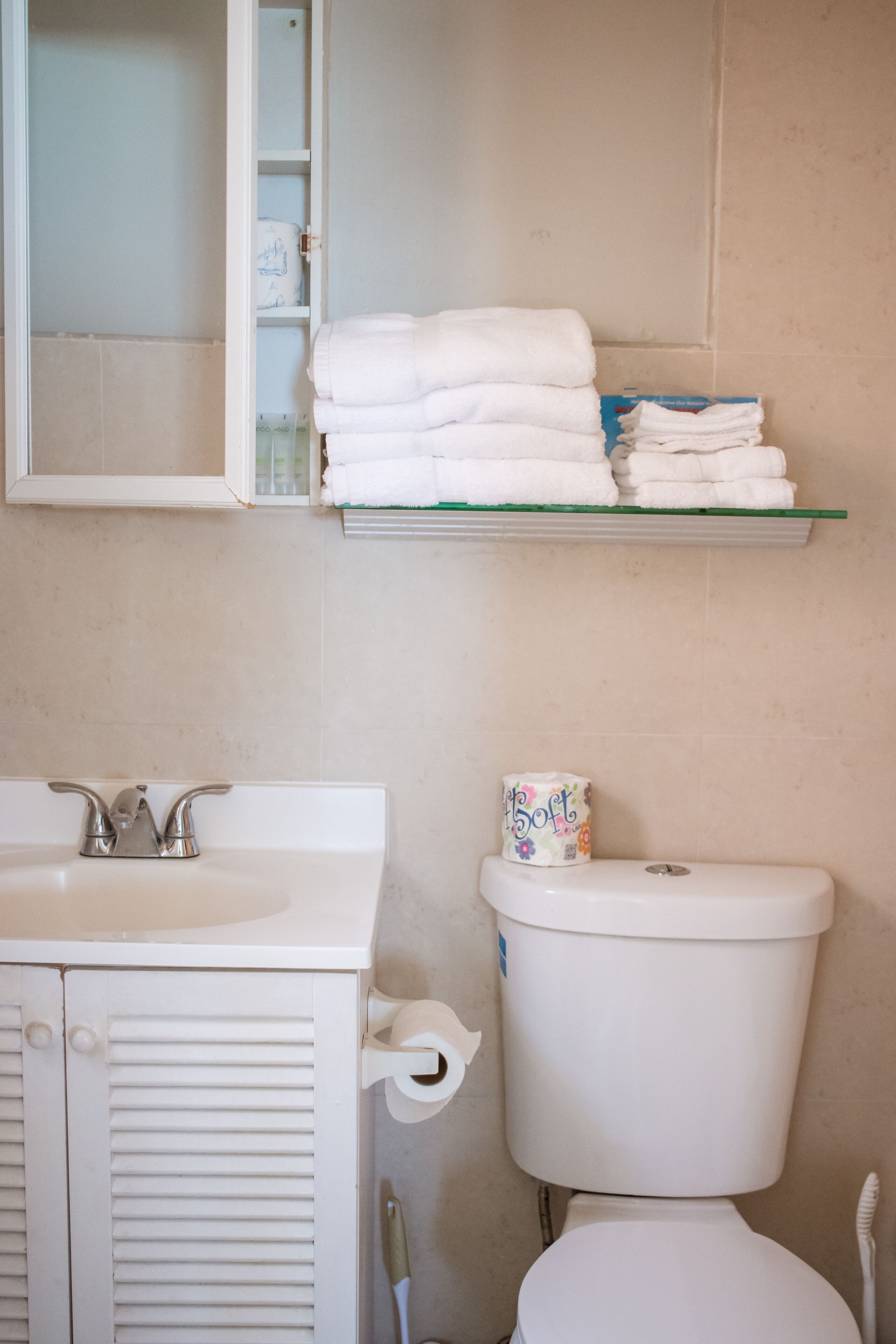 Un baño con un lavamanos blanco, un inodoro y un estante con toallas dobladas.