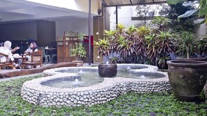 A courtyard with a circular water feature, stone seating, and potted plants. - De Batara Hotel (Bandung)