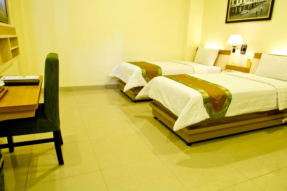 A hotel room with two beds, a desk, and a chair.