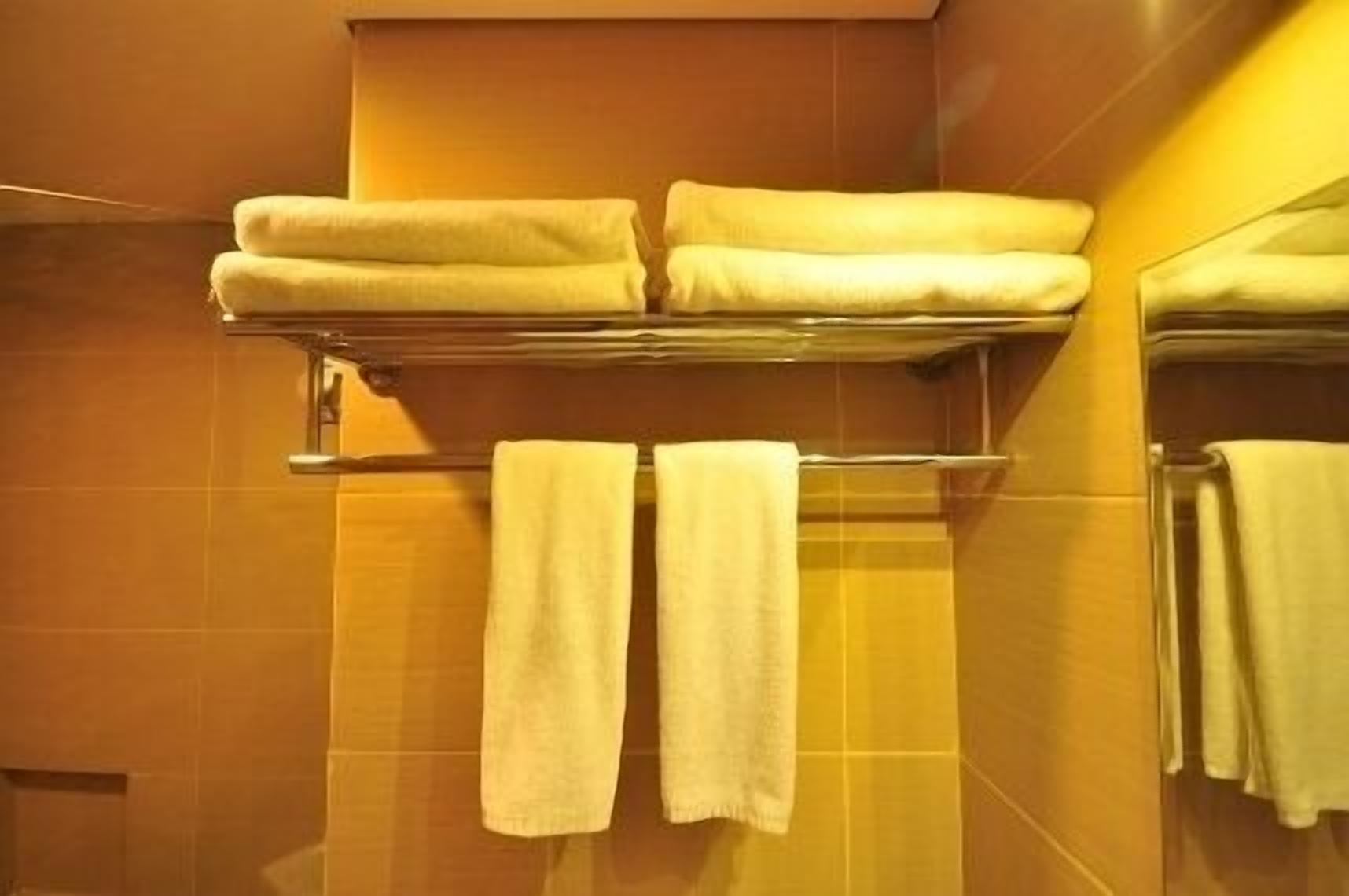 A bathroom with a towel rack holding two folded towels and two towels hanging on the wall.