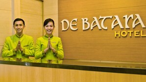 A reception desk at De Batarah Hotel with two staff members standing behind it. - De Batara Hotel (Bandung)