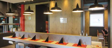 A modern bar area with multiple high tables, bar stools, and pendant lighting.