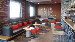 A modern lounge area with a sofa, chairs, and a bar. - Ibis Milano Fiera (Lainate)