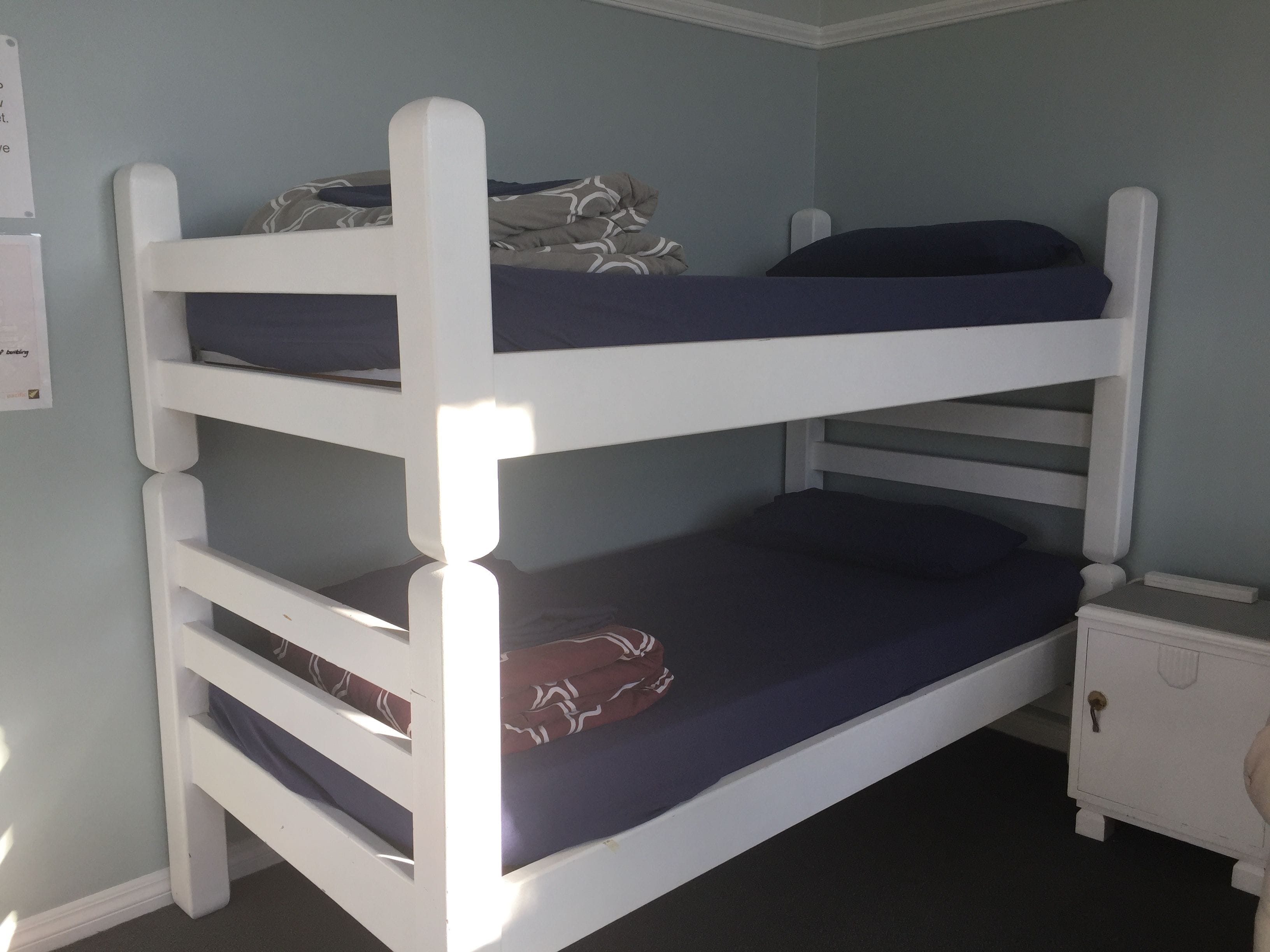 A bunk bed with two levels, a small bedside table, and a nightstand.