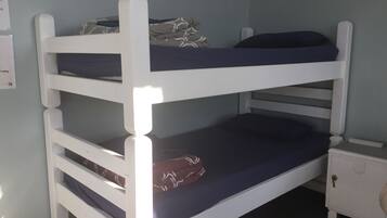 A bunk bed with two levels, a small bedside table, and a nightstand.
