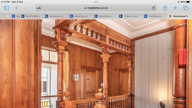 A wooden staircase with ornate balusters and a handrail, leading to a door with a brass handle. - TripInn Modern Motels & Affordable Accommodation (Westport)