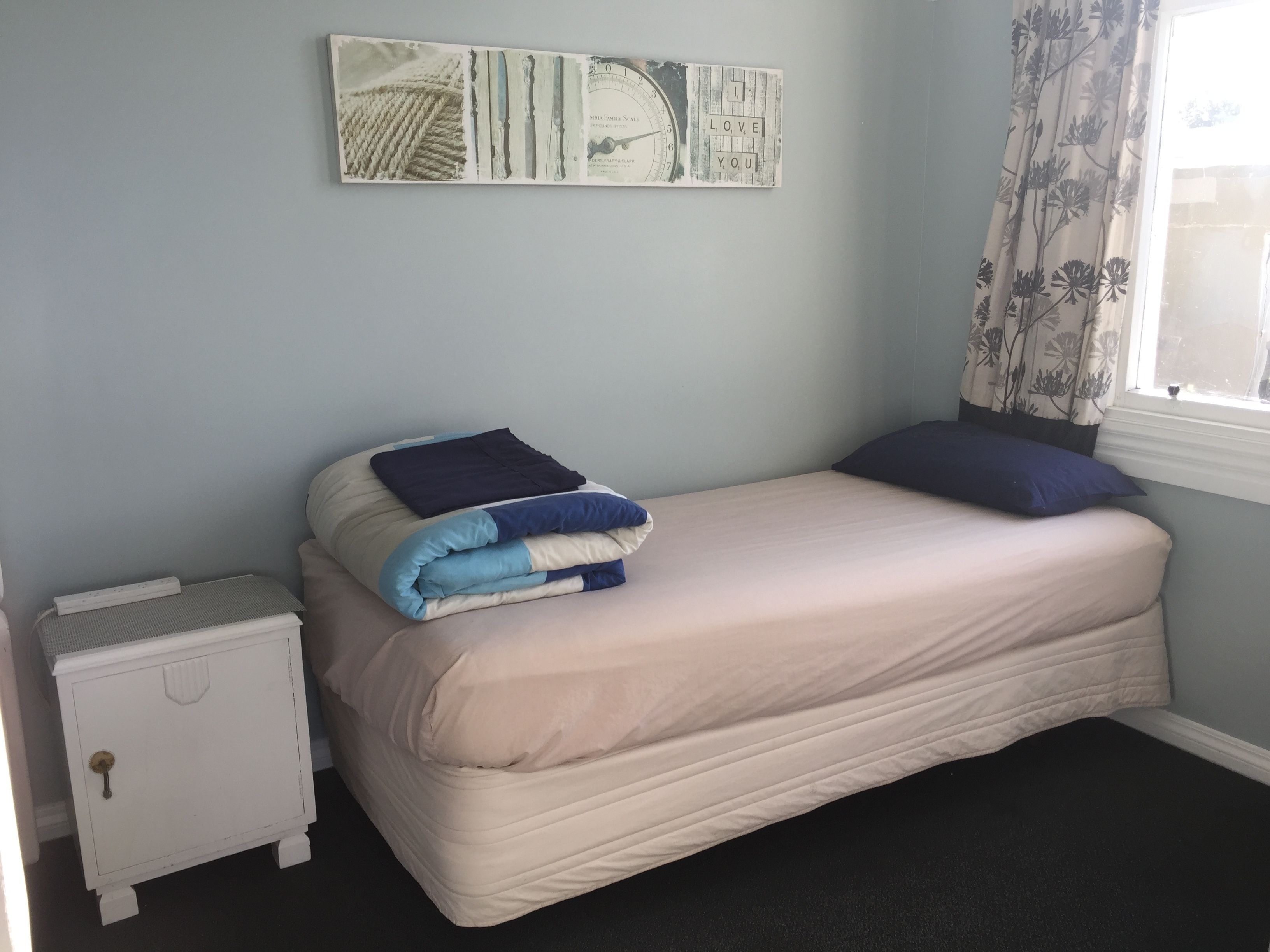 A bedroom with a bed, a nightstand, and a wall clock.