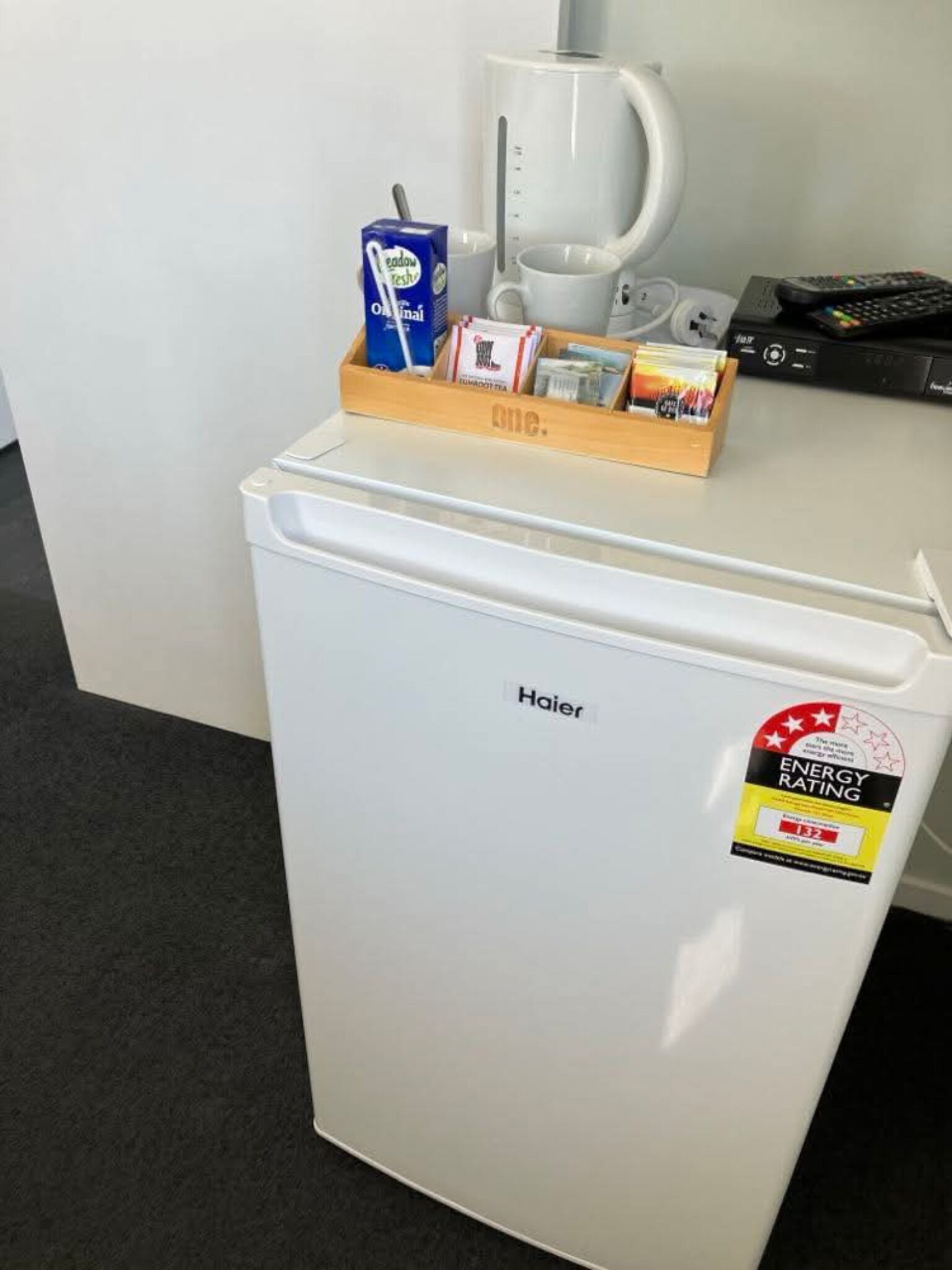 A compact Haier refrigerator with an ENERGY STAR rating sticker, a coffee maker, and a box of instant coffee on top.