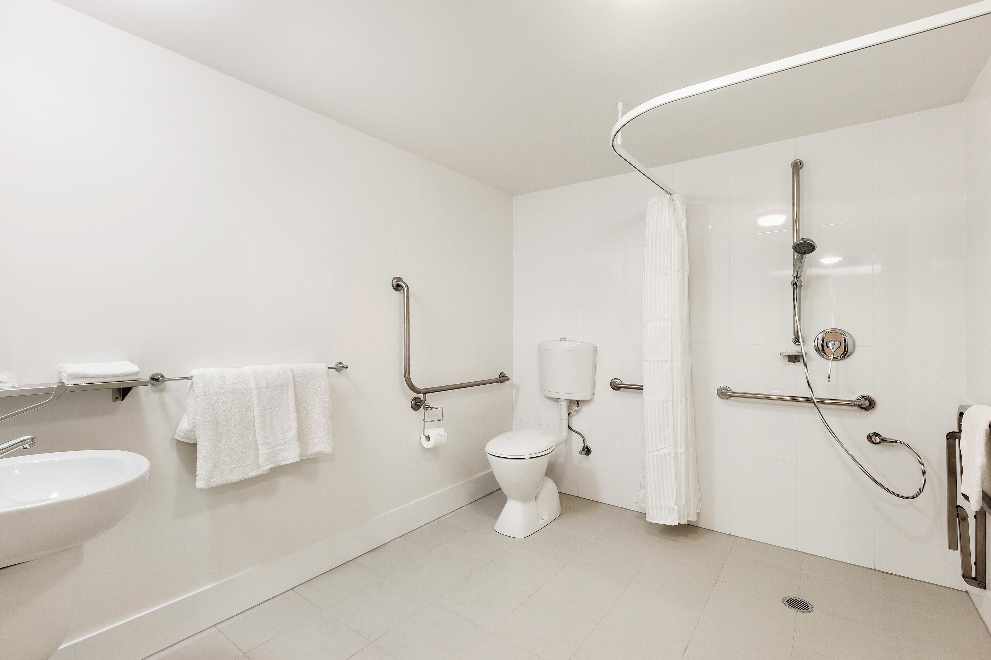 A modern bathroom with a white sink, toilet, and shower area.