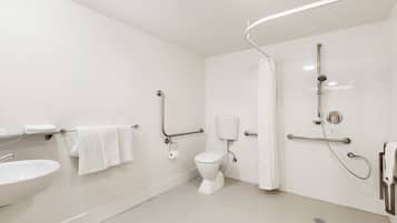 A modern bathroom with a white sink, toilet, and shower area.