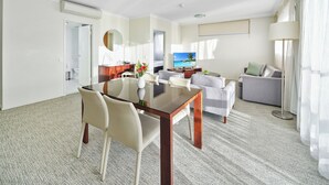 A hotel room with a dining area, a sofa, a TV, and a view of the ocean. - Quest Breakfast Creek (Albion)
