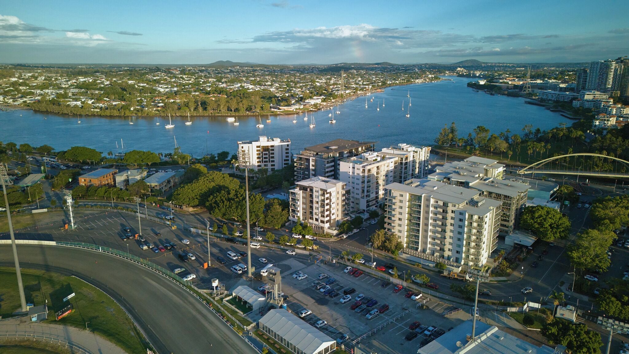 A coastal cityscape with high-rise buildings, a marina with sailboats, and a bridge.