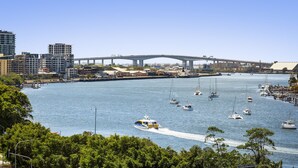 A marina with boats, a bridge, and buildings in the background. - Quest Breakfast Creek (Albion)