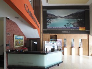 Zona de recepción de hotel con un gran cartel de Cassadua, un cuadro enmarcado en la pared y un cartel grande que anuncia actividades como rafting y paseos de té.