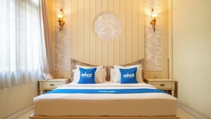 A hotel room with a bed, two nightstands, a circular wall decoration, and two wall-mounted lamps.
