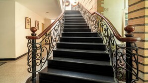 A staircase with ornate metal railings and wooden handrails, leading to an upper floor.