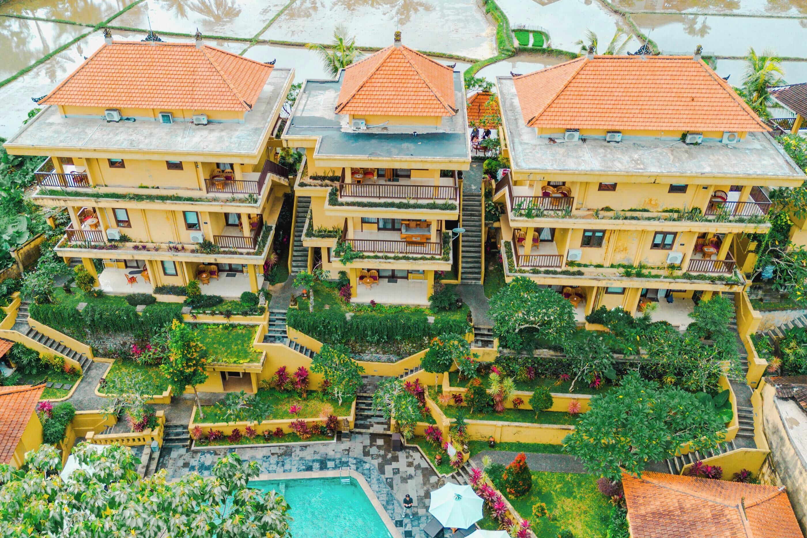 Un hotel de varios pisos con patio central, balcones y piscina.