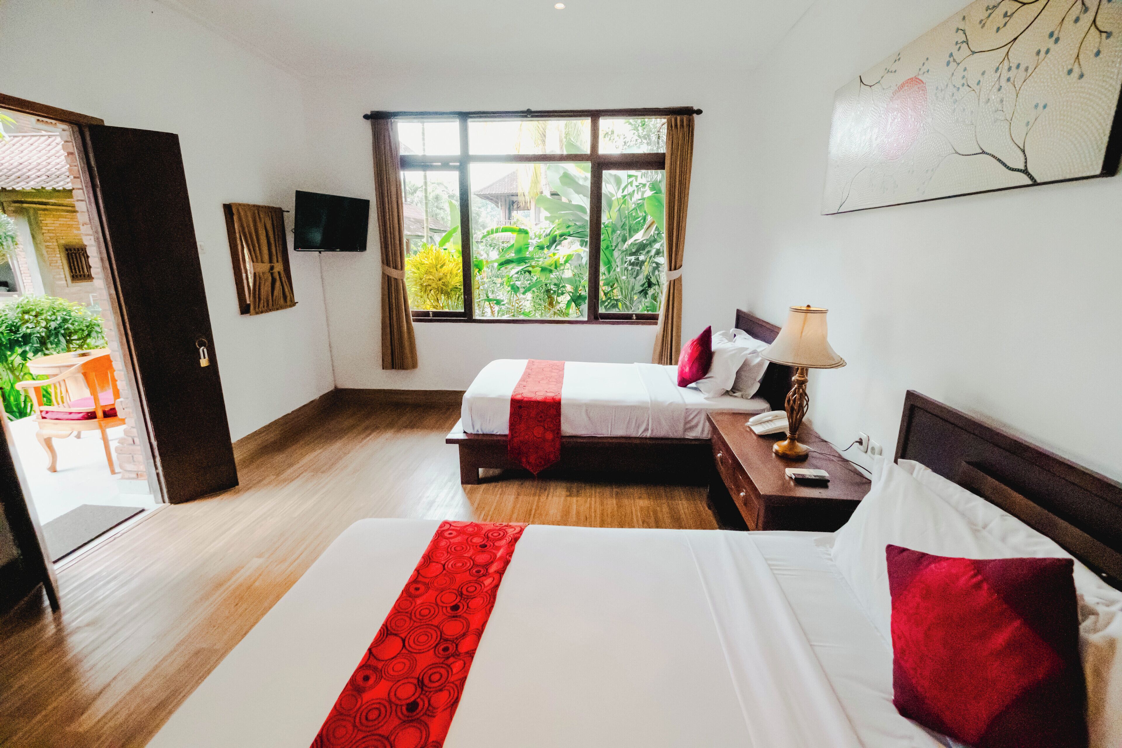 A hotel room with two beds, a window with curtains, a flat-screen TV, and a painting on the wall.