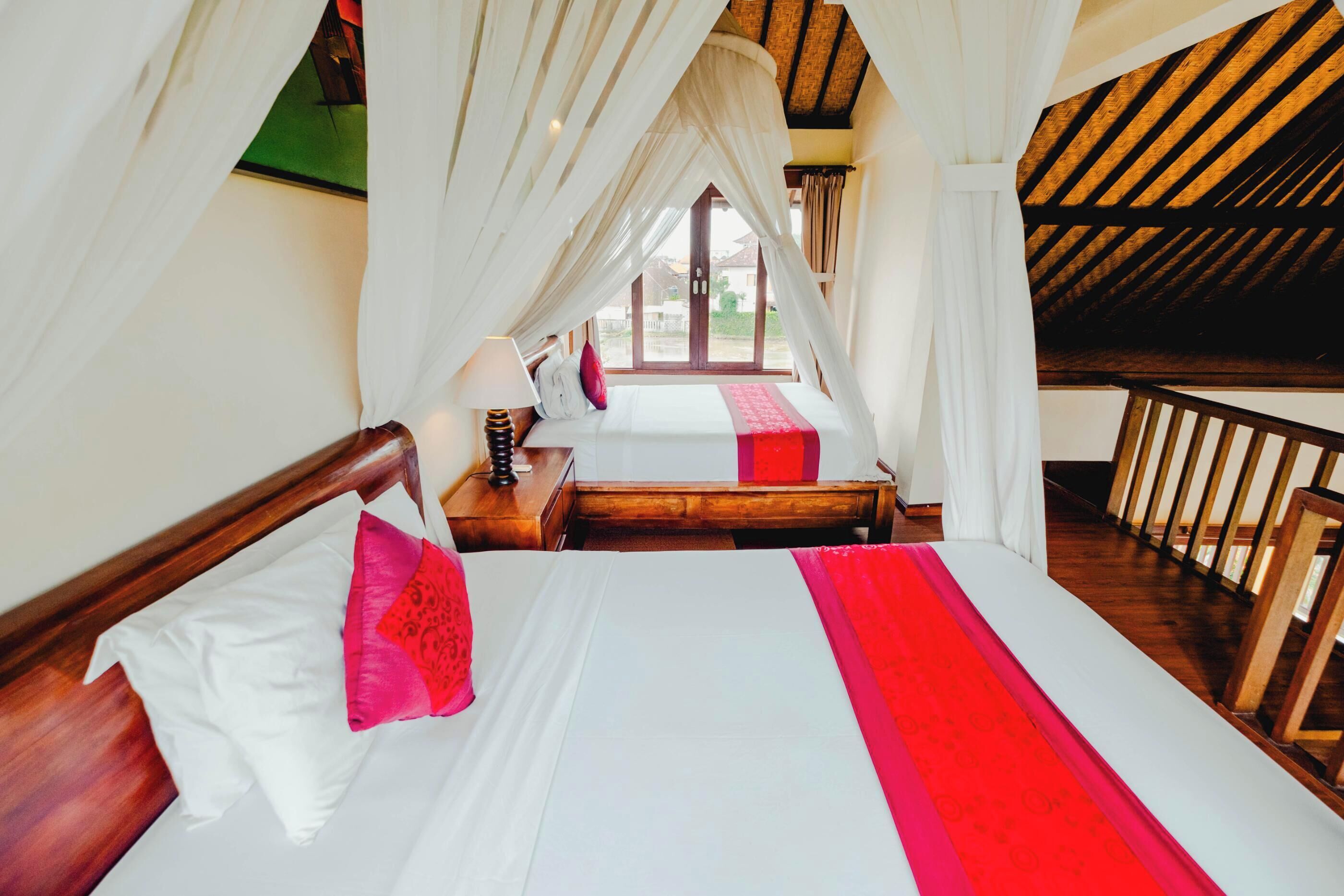 Un dormitorio con cama, mesita de noche y ventana con cortinas.