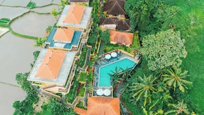Ein Luftbild zeigt ein Resort mit mehreren Gebäuden, einem Swimmingpool und üppiger Vegetation.