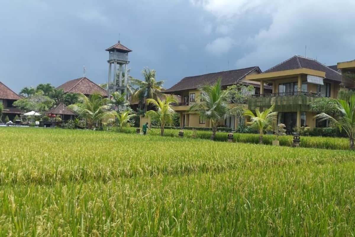 A hotel with multiple buildings, a water tower, and a lush green field in the foreground.