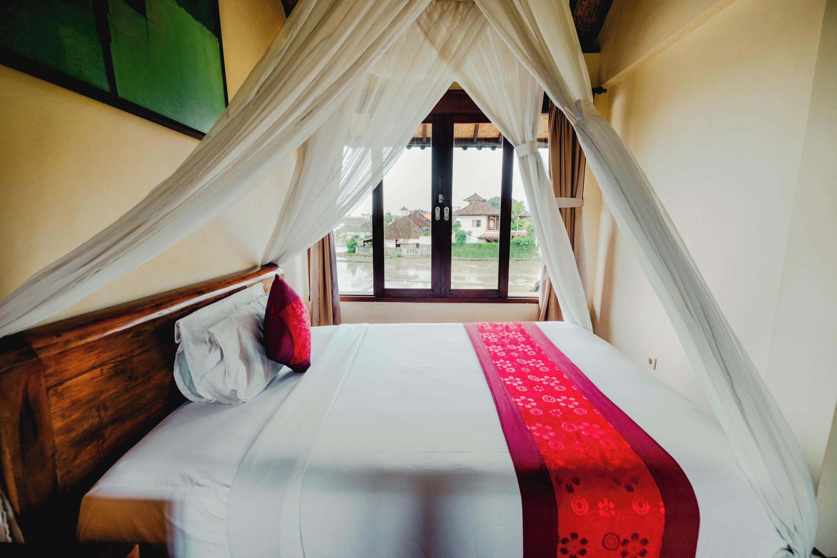 A bed with a canopy, a window, and a view of the outside.