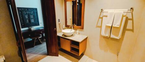 A modern bathroom with a white sink, a large mirror, and a towel rack.