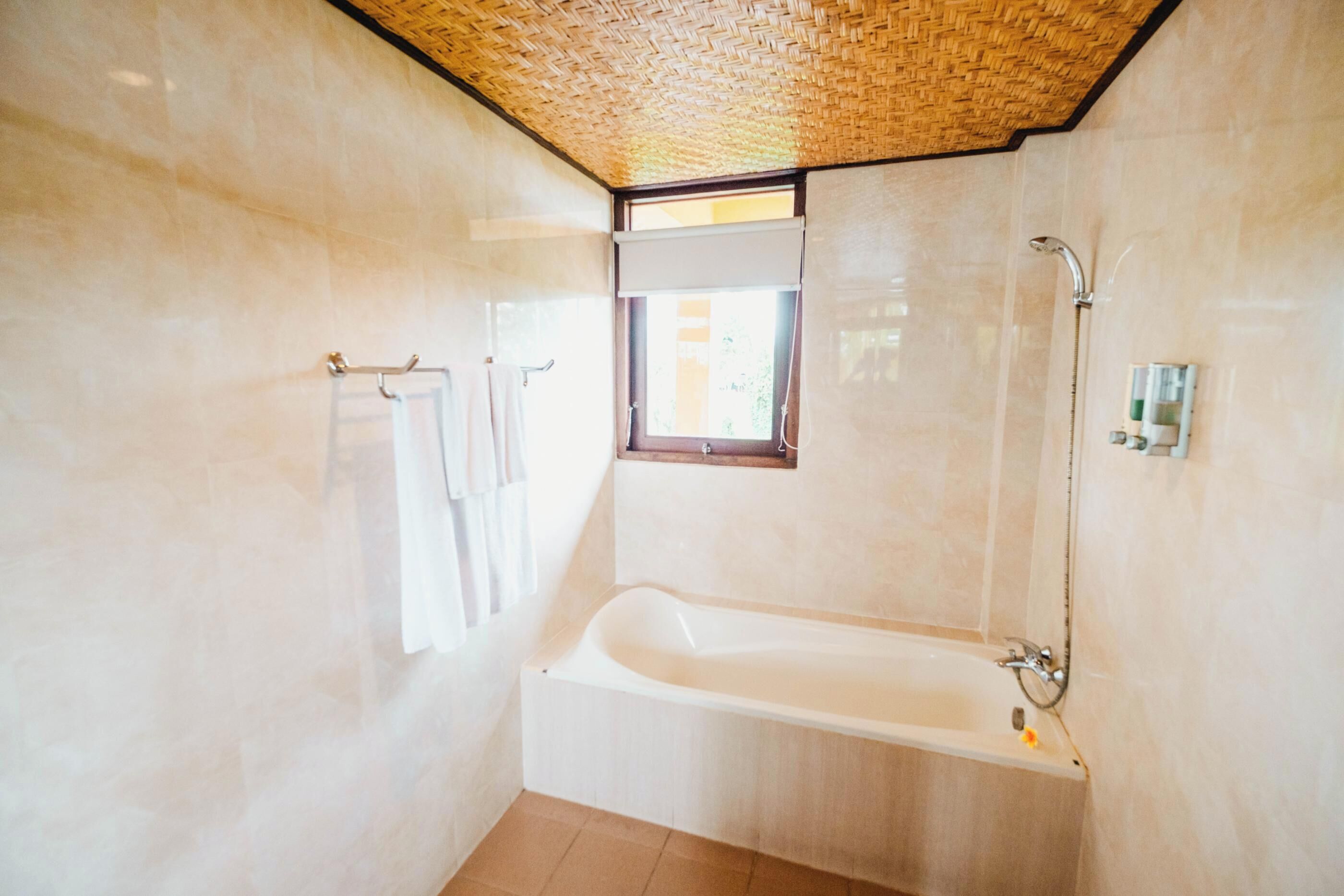 A bathroom with a large bathtub, a window, and a shower.