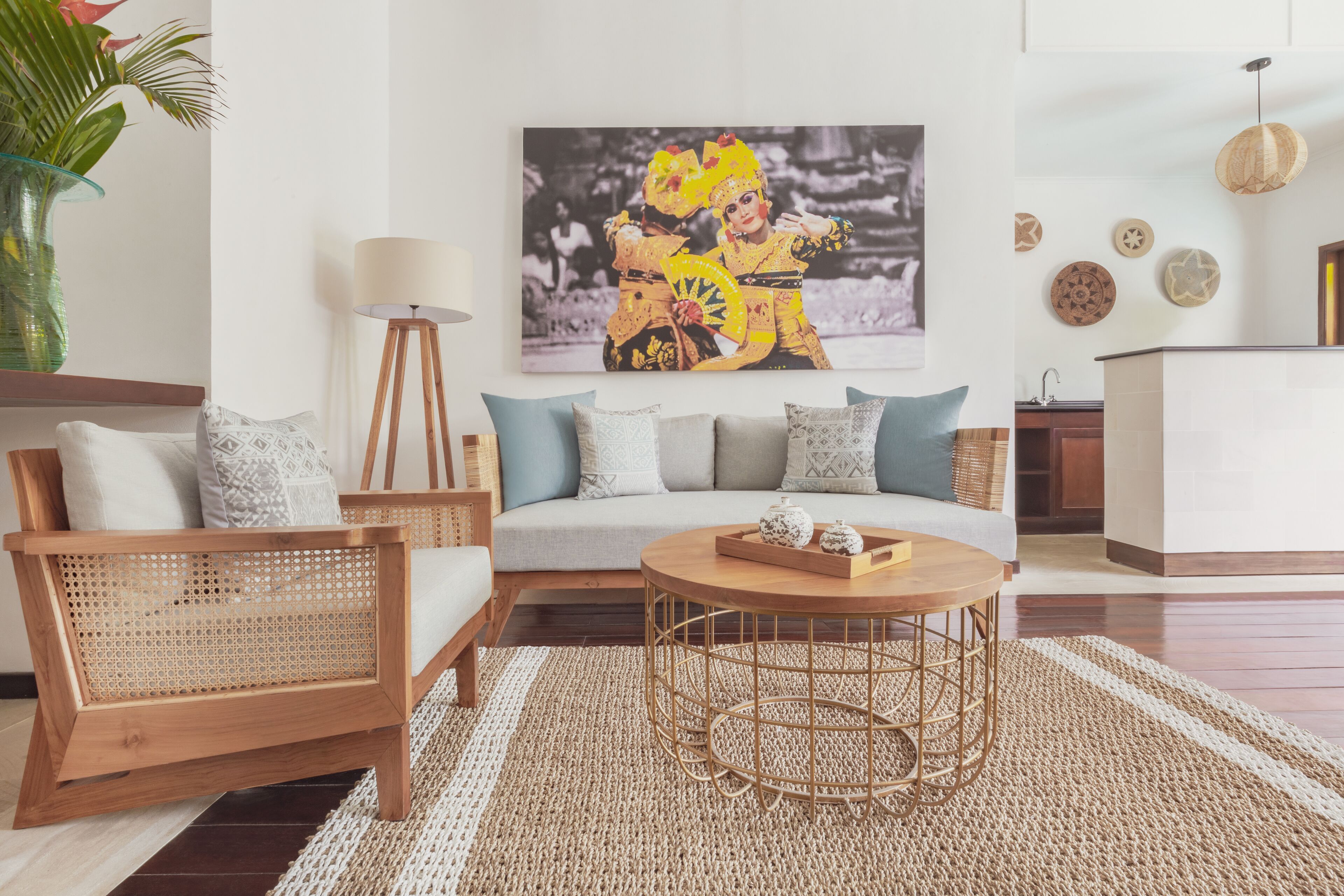 Een woonkamer met een bank, twee houten stoelen, een ronde salontafel en een vloerlamp.