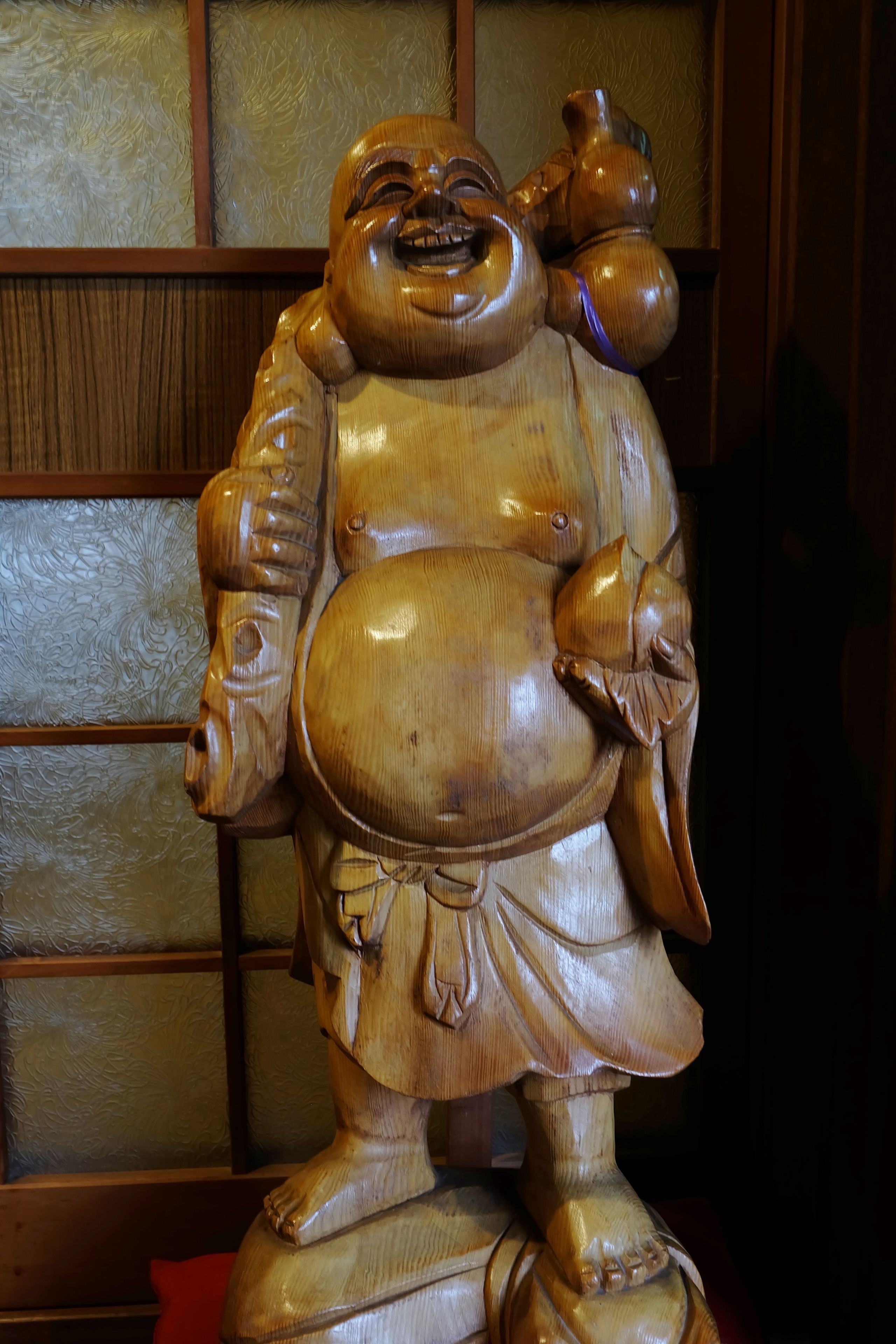 A wooden statue with a large belly, holding a child and a small object.