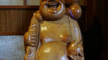 A wooden statue with a large belly, holding a child and a small object.