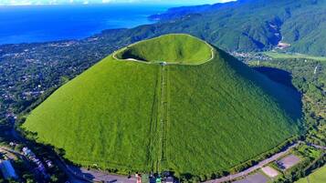 An aerial view of a green hill with a road leading to a small settlement.