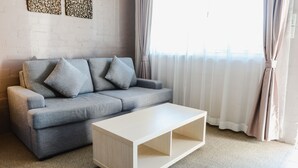 A modern living room with a grey sofa, two cushions, and a white coffee table. - Balan Village Motel (Bomaderry)