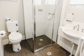 A bathroom with a toilet, a glass-enclosed shower, and a sink. - Balan Village Motel (Bomaderry)