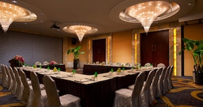 A conference room with a long table, chairs, and chandeliers.