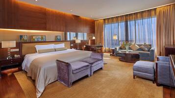 A spacious hotel room with a large bed, a sofa, a coffee table, and a TV.