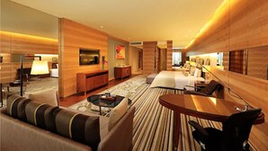 A modern hotel room with a large bed, a sitting area with a sofa and coffee table, a desk, and a TV. - HJ International Hotel (Dongguan)