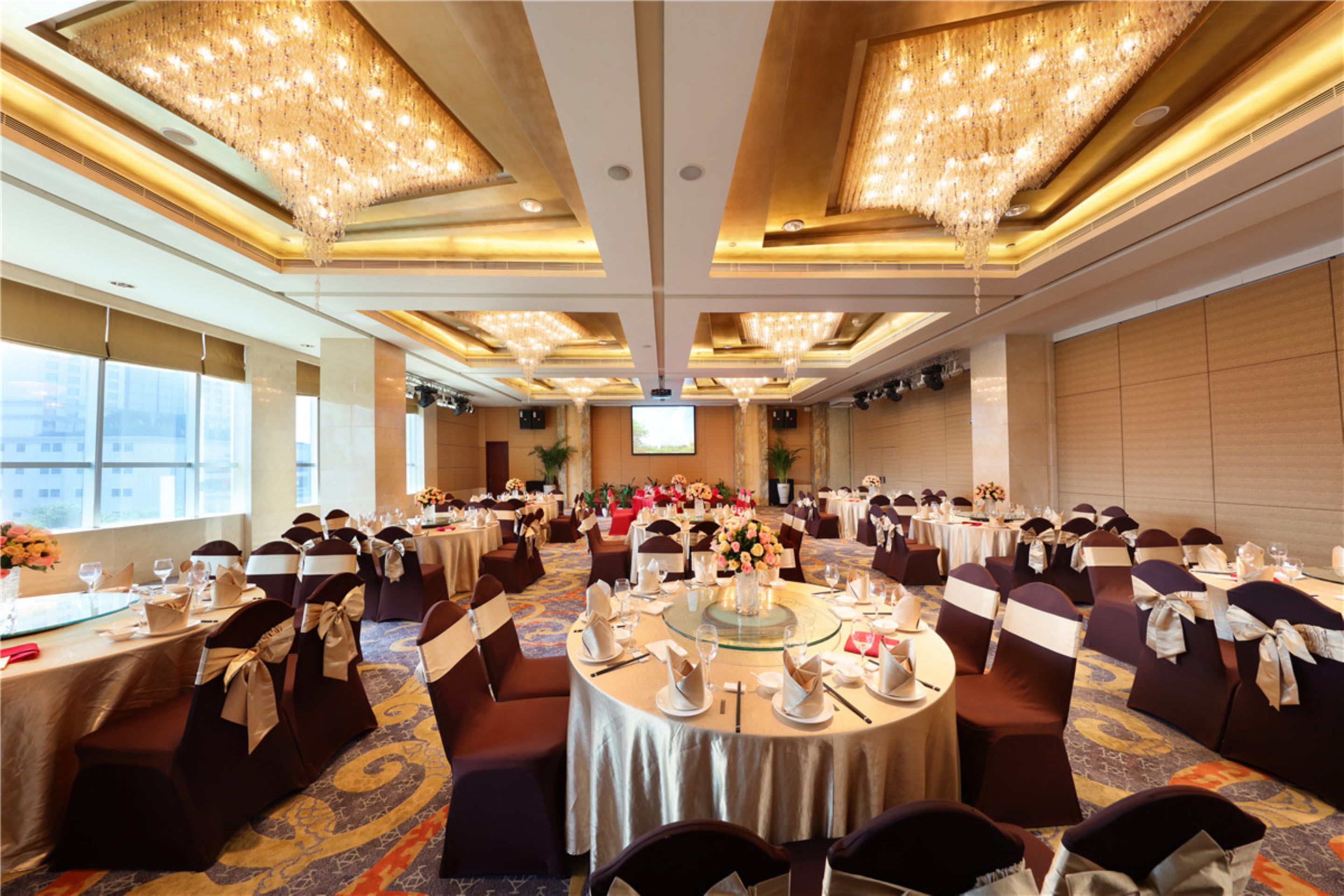 Un salón de banquetes con mesas redondas, sillas y candelabros.