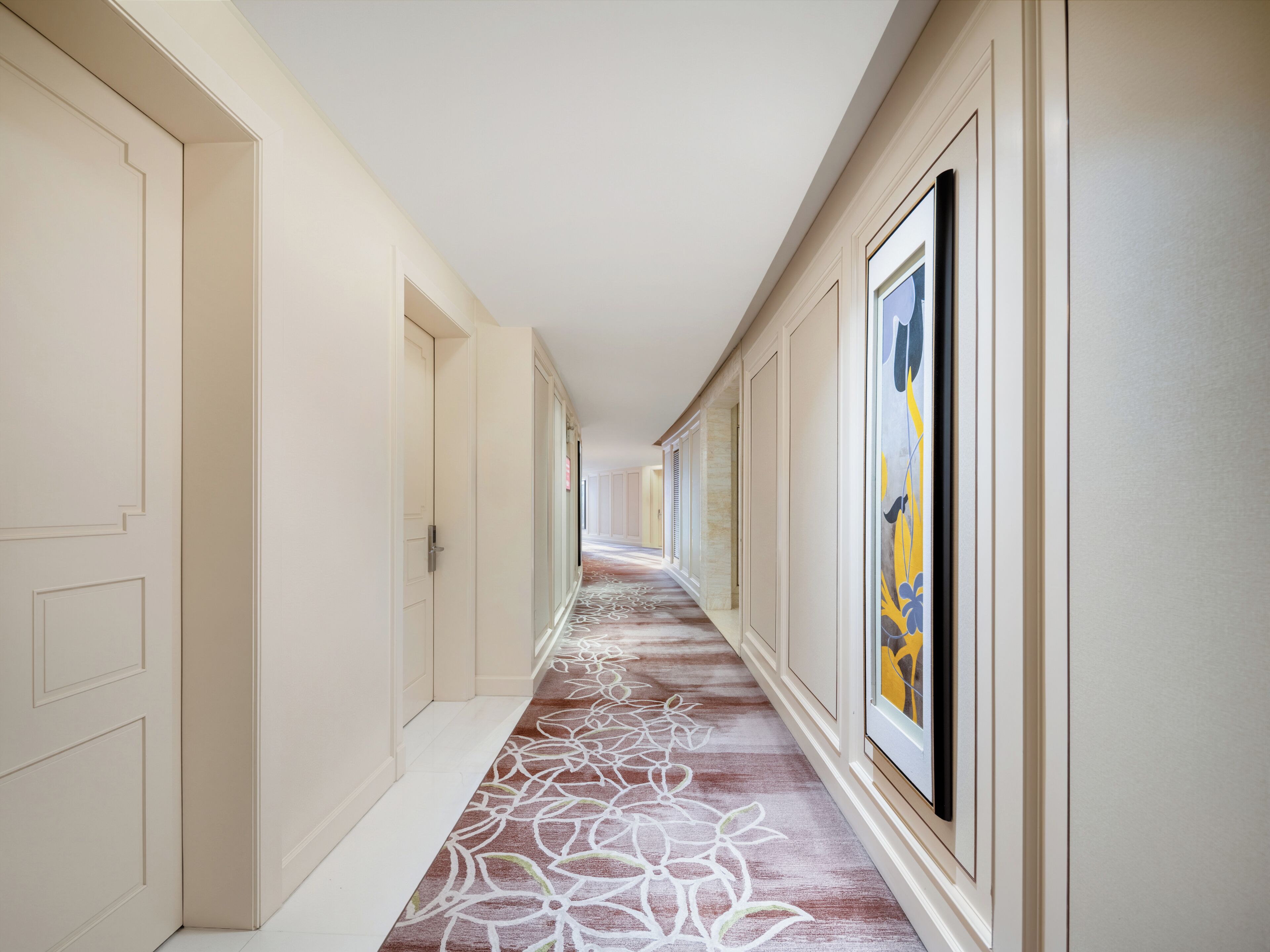 A long, narrow hallway with cream-colored walls and a patterned carpet.