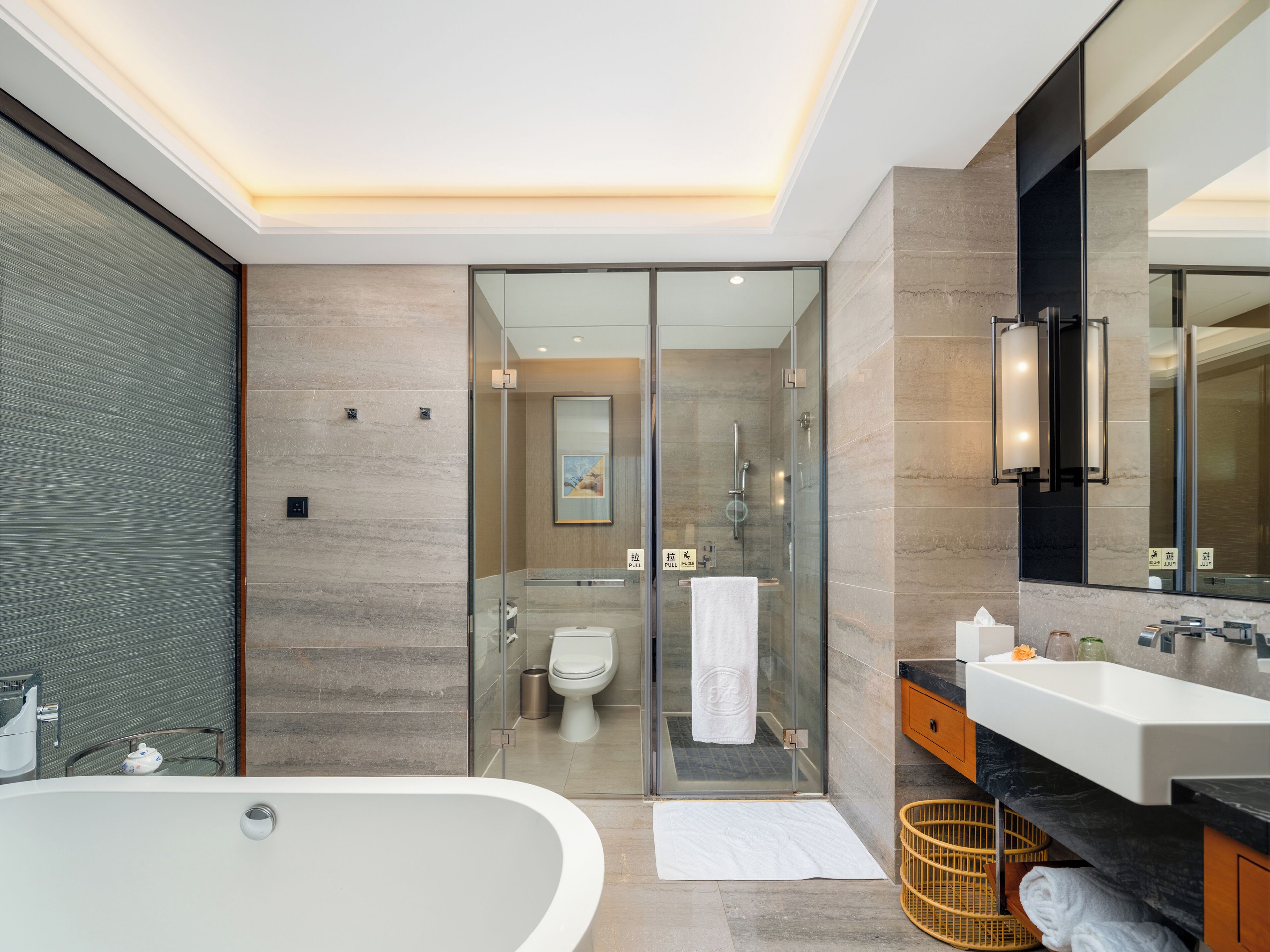 A modern bathroom with a large bathtub, a glass-enclosed shower, and a vanity with a mirror.
