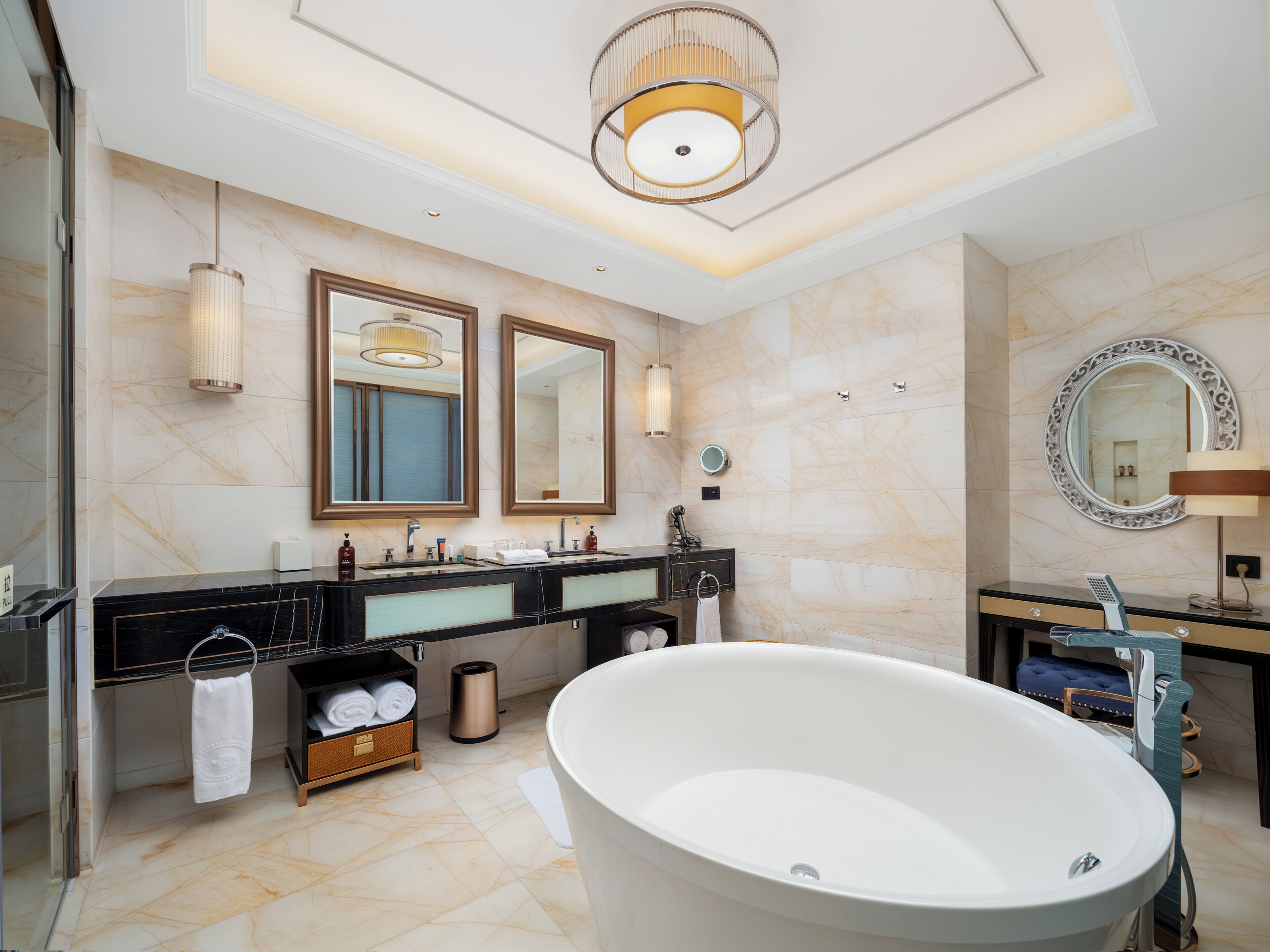 A modern bathroom with a freestanding bathtub, dual sinks, and large mirrors.