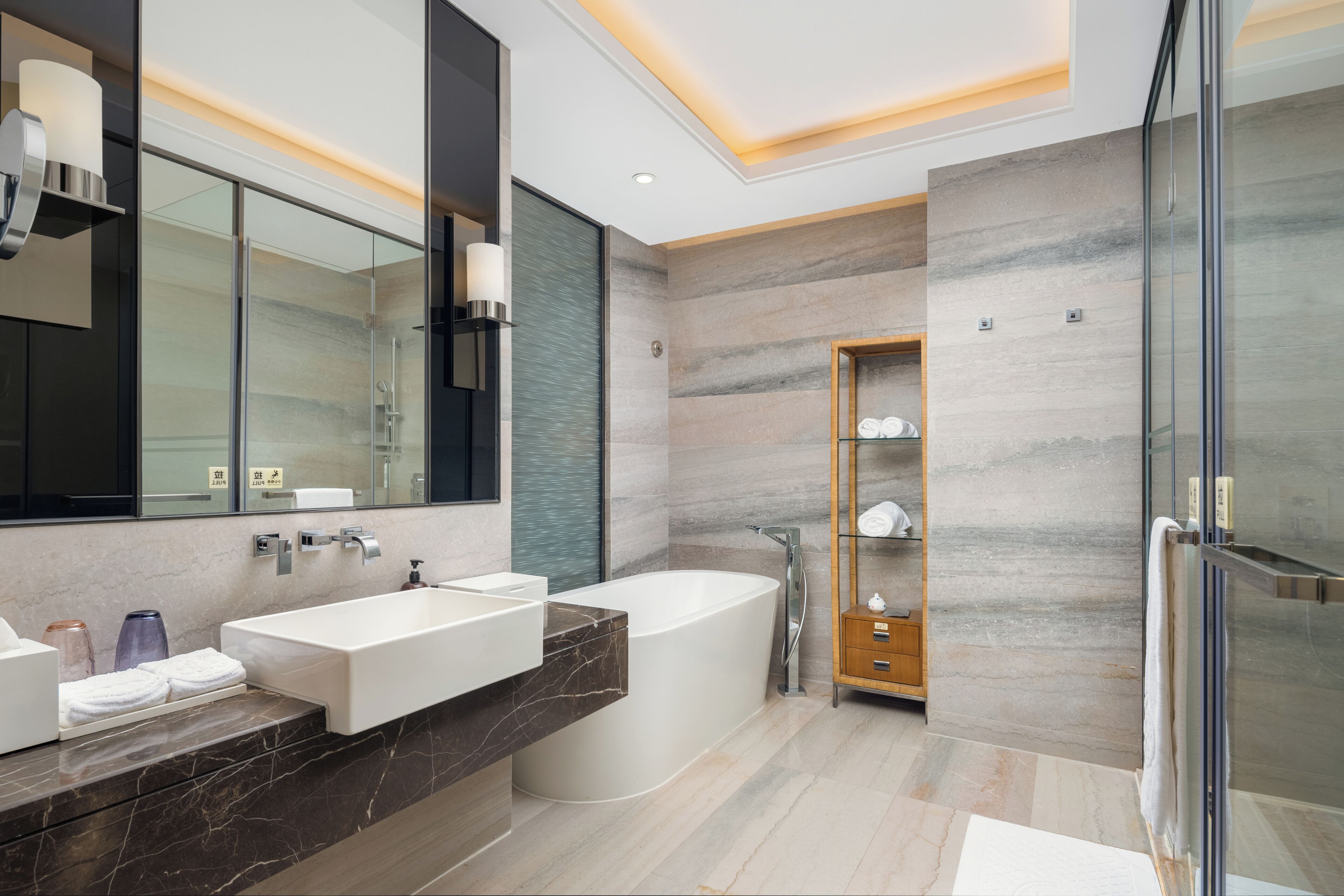 A modern bathroom with a large bathtub, a vanity with two sinks, and a glass shower enclosure.